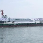 　熊本港を船で出発する九州新幹線つばめの車両＝２９日午後、熊本市