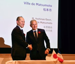 　握手する長野県松本市の臥雲義尚市長（左）とシャンボール国立公園トップのピエール・デュブルイユ氏＝１日午後、東京都港区