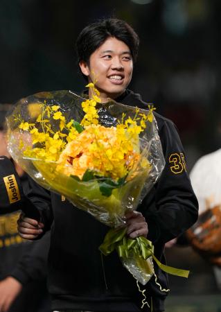 　セ・リーグ記録に並ぶ１６奪三振を達成し、花束を手に笑顔を見せる阪神・才木＝甲子園