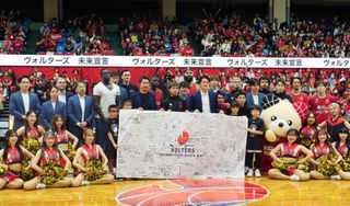 　試合後に記念撮影するバスケットボールＢ２熊本の選手とＯＢら＝１２日、熊本県立総合体育館