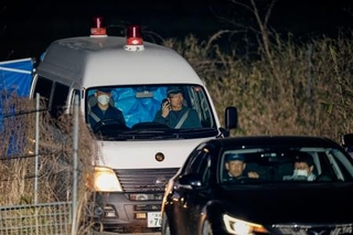 　身元不明の遺体が見つかった京都府南丹市の現場付近を出る警察車両。後部座席がブルーシートで覆われていた＝１３日午後９時２３分