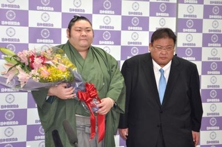 　引退記者会見を終え花束を手にする元幕内剣翔。右は追手風親方＝１４日、東京・両国国技館