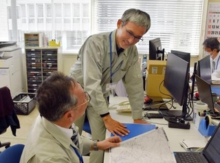 　石川県珠洲市役所で業務主任の門前修さん（手前）と話す熊本市職員の後藤升郎さん＝１４日