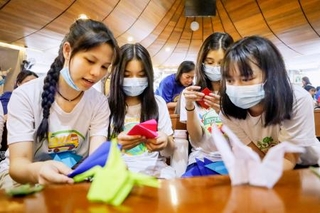 　折り鶴の作り方を話し合う学生ら＝２１日、マニラ首都圏ケソン市（共同）