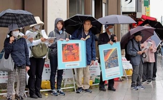 　空襲連の集会で被害が描かれたパネルを掲げる参加者ら＝２３日午後、東京都台東区