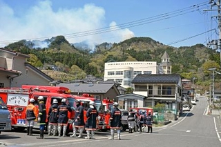 　避難所となっている吉里吉里学園小学部（奥）近くから立ち上る煙＝２４日午前、岩手県大槌町