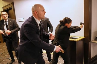 　２５日、ホワイトハウス記者会主催の夕食会会場で銃を構える当局者ら＝ワシントン（ＡＰ＝共同）