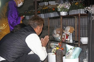 　関越道バス事故から１４年となり、献花台の前で手を合わせる遺族＝２９日午前４時４０分、群馬県藤岡市