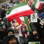 　イランの首都テヘランで国旗を掲げながら行進する人々＝３月（ゲッティ＝共同）