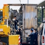 　炎上した大型トラックを調べる三重県警の捜査員ら＝３日午前、三重県菰野町