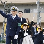 　新１年生と手をつないで横断歩道を渡る警視庁の筒井洋樹警視総監（手前左）＝６日午後、東京都大田区