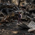 　レバノンの首都ベイルートで、イスラエル軍の攻撃により焼け焦げた車両付近を歩く住民＝１０日（ＡＰ＝共同）