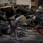 　レバノンの首都ベイルートで、イスラエル軍の攻撃で焼け焦げた車両の前に立つ男性＝１０日（ＡＰ＝共同）