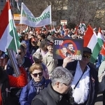 　ハンガリーの首都ブダペストで、ウクライナのゼレンスキー大統領らの顔写真と共に「戦争をやめろ」と記したプラカードを掲げて行進するフィデス支持者ら＝３月（共同）