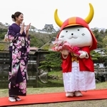 　２０回目の誕生日を祝う特別記念イベントで、大橋悠依さんから花束を受け取った「ひこにゃん」。奥は彦根城＝１３日午前、滋賀県彦根市