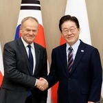 　１３日、ソウルでの会談で握手する韓国の李在明大統領（右）とポーランドのトゥスク首相（共同）