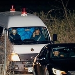 　身元不明の遺体が見つかった京都府南丹市の現場付近を出る警察車両。後部座席がブルーシートで覆われていた＝１３日午後９時２３分