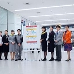 　モバイルバッテリーの取り扱い変更を周知するポスターと航空各社の社員ら＝１４日午後、羽田空港