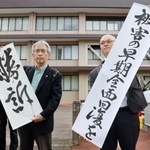 　生活保護減額訴訟の控訴審判決後、「勝訴」などと書かれた垂れ幕を掲げる弁護士ら＝１７日午後、福岡高裁宮崎支部前