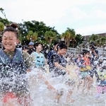 　水しぶきを上げて海に入る子どもたち＝１９日午前、鹿児島県・奄美大島