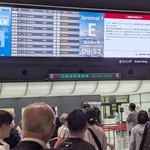 　管制トラブルによる遅延などを伝える羽田空港内の電光掲示板＝２１日午前９時５３分