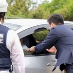 　通行車両を呼び止め、情報提供を求めるチラシを配布する静岡県警の捜査員＝２１日午前、浜松市中央区