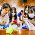 　折り鶴の作り方を話し合う学生ら＝２１日、マニラ首都圏ケソン市（共同）