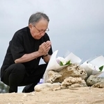 　沖縄県名護市辺野古沖での転覆事故の現場を臨む「瀬嵩の浜」で手を合わせる玉城デニー知事＝２１日午後