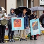 　空襲連の集会で被害が描かれたパネルを掲げる参加者ら＝２３日午後、東京都台東区