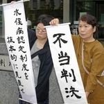 　水俣病患者認定を巡る訴訟の判決で、「不当判決」などと書かれた紙を掲げる支援者ら＝２３日午後、福岡高裁前