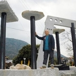 　「旧金毘羅大芝居」（左後方）の鉄柱を使いモニュメントを作った篠原勝之さん＝２００５年３月、香川県琴平町