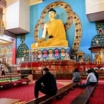 　欧州最大とされるチベット仏教寺院にある仏像の前で祈る人ら＝３月、ロシア南部カルムイキア共和国エリスタ（共同）