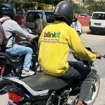 　インド・ニューデリーの路上をバイクで走る「ブリンキット」の配達員（手前）＝１３日（共同）