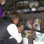 　関越道バス事故から１４年となり、献花台の前で手を合わせる遺族＝２９日午前４時４０分、群馬県藤岡市