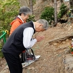 　日航ジャンボ機墜落事故で犠牲となった辻昌憲さんの墓標に手を合わせる板鼻昭さん（手前）と妻文子さん＝２９日午前、群馬県上野村