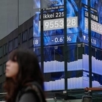 　３０日、電光掲示板の前を歩く人＝東京（ＡＰ＝共同）