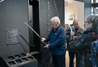 　備前長船刀剣博物館で刀剣のレプリカを持つフランス人来館者＝３月、岡山県瀬戸内市