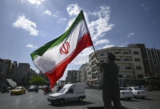 　イラン・テヘランの街頭で国旗を掲げる男性＝４月（共同）