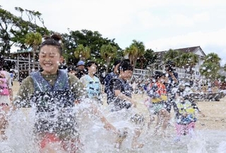 　水しぶきを上げて海に入る子どもたち＝４月、鹿児島県・奄美大島