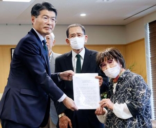 　被爆体験者の岩永千代子さん（右）らから早期救済に向けた要望書を受け取る長崎県の平田研知事＝１１日午後、長崎県庁