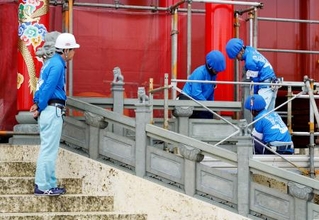 　首里城正殿の正面に高欄を設置する作業員＝１２日午前、那覇市