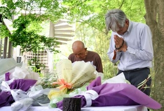 　空自機墜落事故から１年となり、献花台の前で手を合わせる人たち＝１４日午後、愛知県犬山市