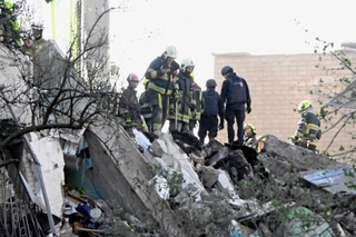 　がれきの下敷きになった人々を捜索する救急隊員ら＝１４日、ウクライナ・キーウ（共同）