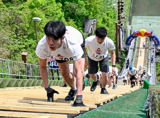 　スキージャンプ台を駆け上がる人たち＝１６日午前、札幌市の大倉山ジャンプ競技場
