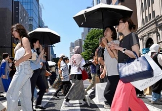 　日傘を差して東京・銀座を歩く人たち。都心は今年初の真夏日となった＝１７日午後