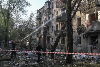 　ウクライナ・ドニプロで、ロシアのミサイル攻撃により損壊した建物付近で活動する消防士＝１８日（ロイター＝共同）