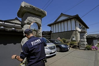 　強盗殺人事件現場の住宅に規制線を張る警察官＝１７日午前、栃木県上三川町