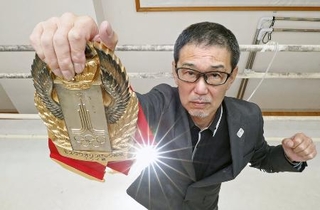 　「モスクワオリンピック候補」と刻まれたベルトを掲げる木庭浩一さん＝２０２０年、熊本市