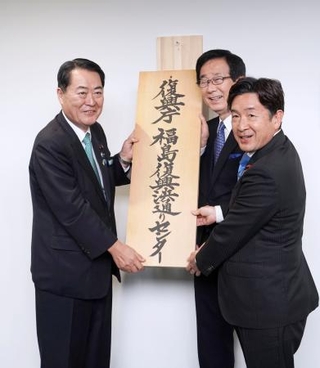 　「福島復興浜通りセンター」の開所式で看板を掛ける牧野復興相（左）＝２４日午後、福島県双葉町