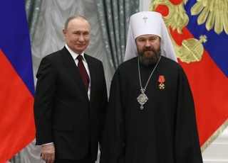 　モスクワのクレムリンでプーチン大統領（左）から国家勲章を受けたロシア正教会のイラリオン対外教会関係局長（当時）＝２０２２年２月（タス＝共同）